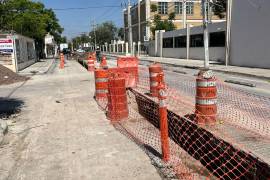 Vallas y toneles de plástico advierten del nuevo pozo en el pavimento abierto recientemente.