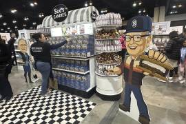 Un trabajador de dulces See's Candy reabastece la exhibición junto a un recorte de Warren Buffett en la sala de exhibiciones de la junta de accionistas de Berkshire Hathaway, el viernes 2 de mayo de 2025 en Omaha, Nebraska. FOTO: