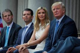 Donald Trump sentado con sus hijos, de izquierda a derecha, Eric Trump, Donald Trump Jr. e Ivanka Trump durante una ceremonia de inauguración del Trump International Hotel el 23 de julio de 2014 en Washington.