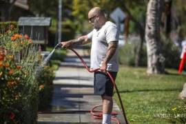 Un vecino riega su jardín a pleno sol, una práctica que las autoridades piden evitar.
