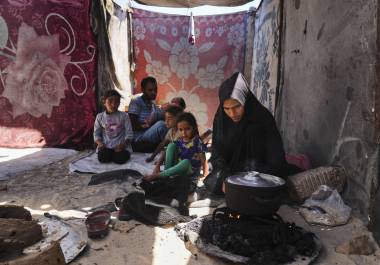 Nouf Al-Arja, de 30 años, que sufre desnutrición, cocina para su familia dentro de su tienda de campaña en un campamento para palestinos desplazados en Muwasi, Khan Younis, Gaza.